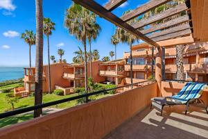 a balcony with a chair and palm trees at Front Line Beach Townhouse Estepona in Estepona