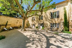 a large stone building with a tree in the yard at La Grange Bessac in Violès