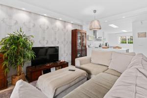 a living room with a couch and a tv at Front Line Beach Townhouse Estepona in Estepona