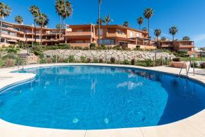 a large blue swimming pool in front of a building at Front Line Beach Townhouse Estepona in Estepona