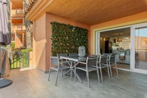 a table and chairs on a patio with a green wall at Front Line Beach Townhouse Estepona in Estepona