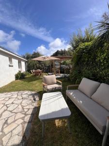 a patio with a couch and a table and an umbrella at Maison et Bonheur in Batz-sur-Mer