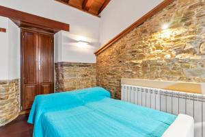 a bedroom with a bed and a stone wall at C de Alborada del eo in Villameitide