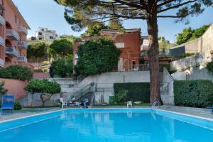 a swimming pool with a tree and some buildings at Casa Sole e Mare in Arenzano