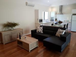 a living room with a black couch and a table at Jarrah Grove Forest Retreat in Rosa Glen