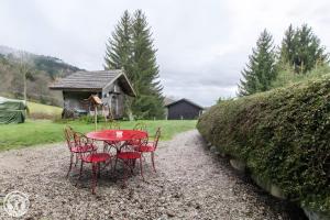 a red table and chairs in front of a house at Gîte Chez Mayon in Orcier