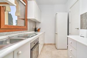 a kitchen with white cabinets and a refrigerator at Apartamento Ombú in La Herradura +17 photos