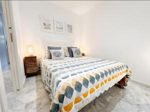a white bedroom with a bed with a colorful comforter at Ola De Mar - Estepona in Estepona +11 photos