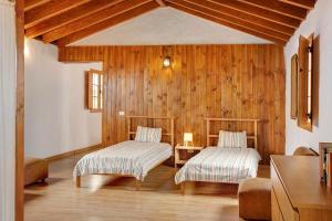 two beds in a room with wooden walls and wooden floors at Mirador de la Abuela in Gáldar