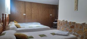 a bedroom with three beds and a stone wall at Casa rural El rincón de Gredos in Navaluenga