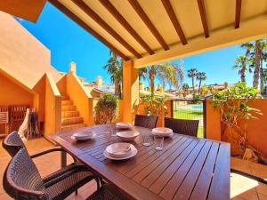 a wooden table and chairs on a patio with a table at Albatros Playa 3 - 1207 in Mar de Cristal