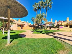 a walkway with umbrellas in a park with palm trees at Albatros Playa 3 - 1207 in Mar de Cristal