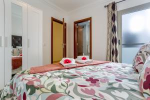 a bedroom with a bed with a floral bedspread at Apartamento Rolycar 202 in Icod de los Vinos