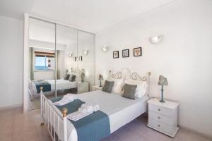 a white bedroom with a bed and a mirror at Casa Néctar in Armação de Pêra