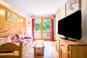 a living room with a couch and a flat screen tv at Appartement Ski Valmeinier in Valmeinier