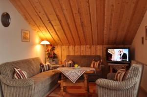 a living room with a couch and a tv at Landhaus Reiser in Grainau