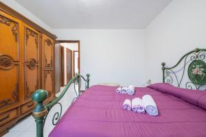a bedroom with a purple bed with slippers on it at Casa vacanze Elifra in San Giovanni Suergiu
