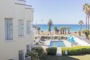 Blick auf einen Pool und das Meer von einem Gebäude aus in der Unterkunft The Beach Hotel in Port Elizabeth