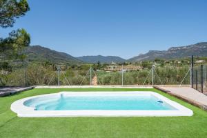 a swimming pool in the grass with mountains in the background at Ca La Cuca in Alforja