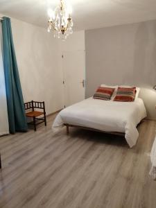 ein Schlafzimmer mit einem großen weißen Bett und einem Kronleuchter in der Unterkunft Les Alliots in Coullons