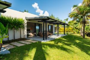 a house with a pavilion on a lawn with palm trees at Villa Kamaya, Chamarel in Chamarel