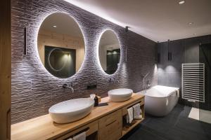 a bathroom with two sinks and two mirrors at Rueper Hof Chalet Ruipa in Valdaora +15 photos