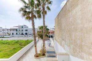 two palm trees on a sidewalk next to a wall at Appartamenti a 50 m dal mare in Torre San Giovanni Ugento