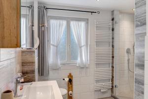 a bathroom with a sink and a window and a shower at Andis Ferienwohnung in Farchant +28 photos