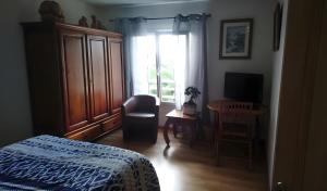 a bedroom with a bed and a chair and a window at Les Orchidées - chambres d'hôtes in Surtainville