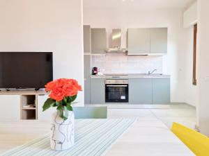 a white kitchen with a vase with orange flowers in it at Porta a Mare Home in Portoferraio