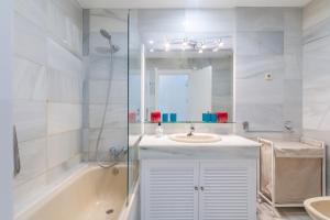 a bathroom with a sink and a tub and a mirror at Superb Large Apartment on the Beach in Marbella +16 photos