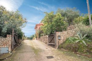 a dirt road with a stone wall and a house at Runcina 2 in San Teodoro