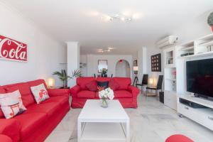 a living room with red couches and a tv at Superb Large Apartment on the Beach in Marbella