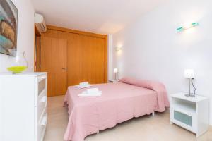 a bedroom with a pink bed and a wooden door at Piso Claudia in Port de Pollensa