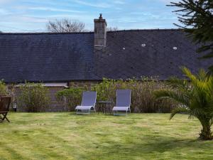 two chairs and a table in a yard at Gite Atelier La Croix Blanche in Kermaria-Sulard