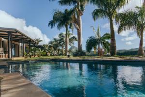 a swimming pool with palm trees in front of a house at Villa Kamaya, Chamarel in Chamarel