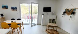 a living room with a dining room table and yellow chairs at Le studio d'Apoline avec piscine in La Tranche-sur-Mer