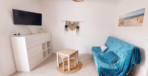 a living room with a blue chair and a tv at Le studio d'Apoline avec piscine in La Tranche-sur-Mer +5 photos