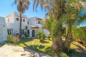 a large white house with palm trees in front of it at Villa Solymar in Cala Serena