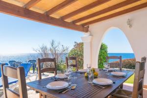 a wooden table on a patio with a view of the ocean at Villa Solymar in Cala Serena