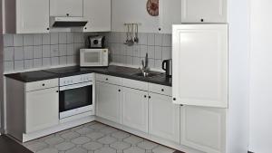 a white kitchen with a sink and a microwave at Sommergarten mit Winternutzung in Karlshagen
