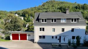 a white house with red doors and a mountain at Sauerland Apartments Willingen in Willingen