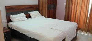 a large bed with white sheets and pillows at Elixir Boarding & Lodging in Bangalore