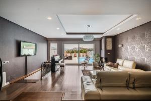 a living room with a couch and a tv at Tranquility Villa with Pool Private Garden & BBQ by PikHost in Tirana