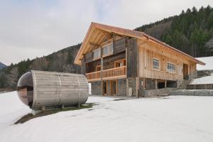 a wooden house with a barrel in the snow at Lisalice appartement in Les Villards-sur-Thônes