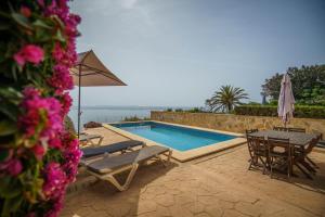 a swimming pool with a table and chairs and an umbrella at Mediterranean Vacation in Mallorca in Cala Pi
