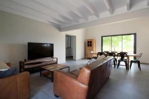 a living room with a couch and a tv and a table at Gîte Basmatho in Yvrac