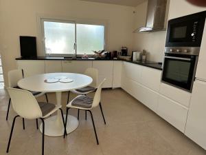 a kitchen with a table and chairs in a kitchen at La douce Escale maison 2 chambres à 50 m de la plage in Royan