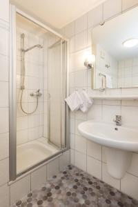 a white bathroom with a shower and a sink at Hotel Liberia in Oberstdorf +49 photos
