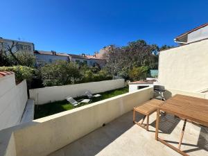 a patio with a table and a bench and a fence at La douce Escale maison 2 chambres à 50 m de la plage in Royan